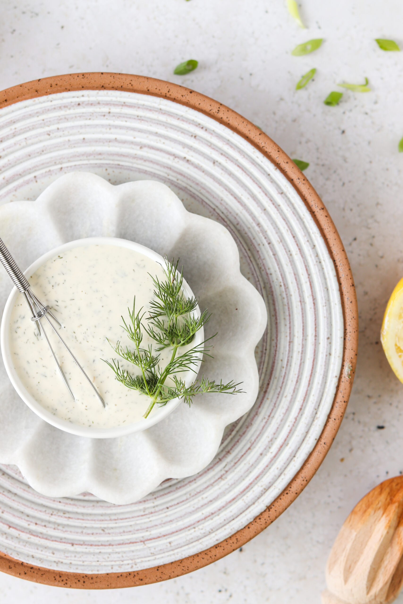 Dill aioli in a small white pull on multiple platters and plates and garnished with fresh dill. 