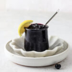 Blueberry maple jam in a jar on a white platter.