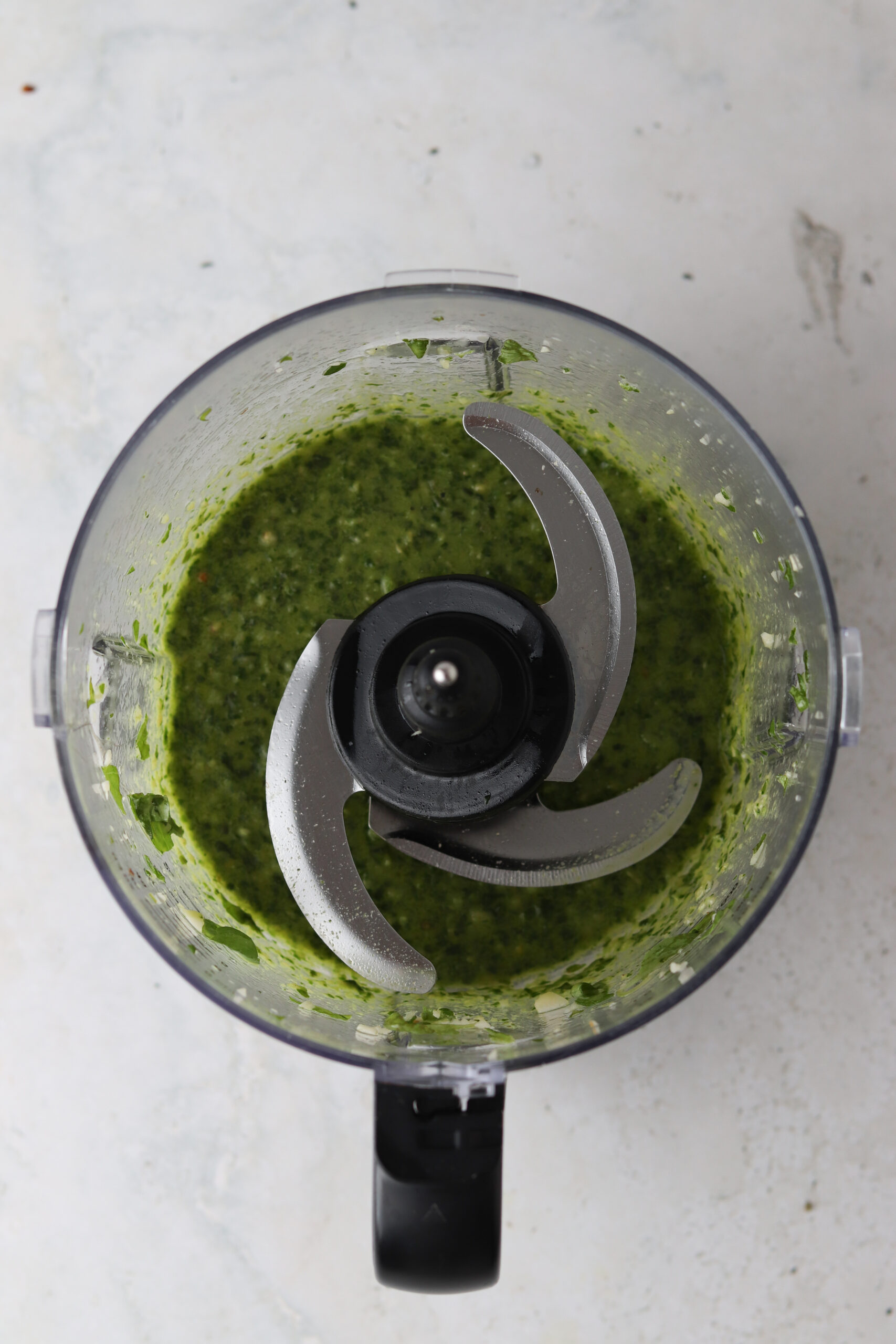 Blended pesto for pesto chicken salad in food processor base.