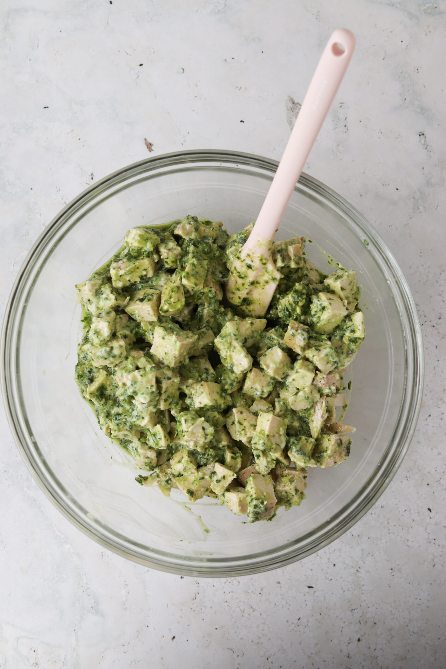 Mixed pesto chicken salad in a large glass bowl. 