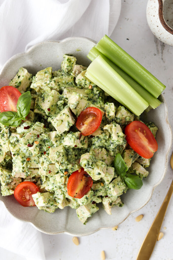 pesto chicken salad in a bowl with tomatoes and celery