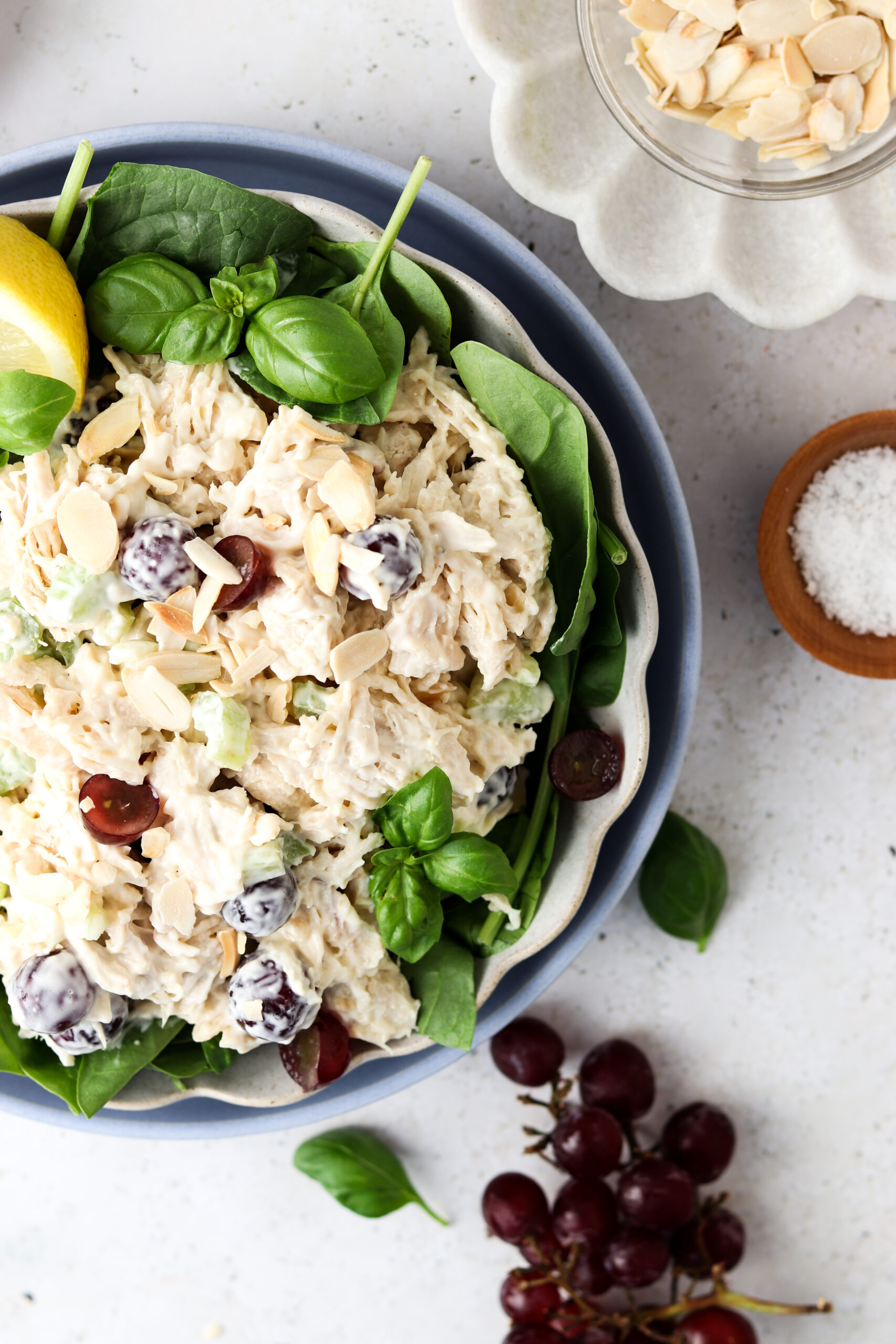 Whole30 chicken salad in a bowl over greens with grapes and almond slices.