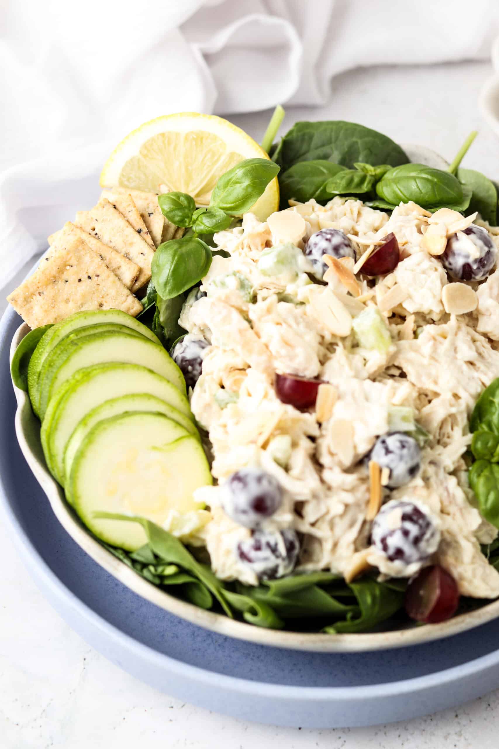 Whole30 chicken salad in a bowl with greens, gluten free crackers, and zucchini slices.