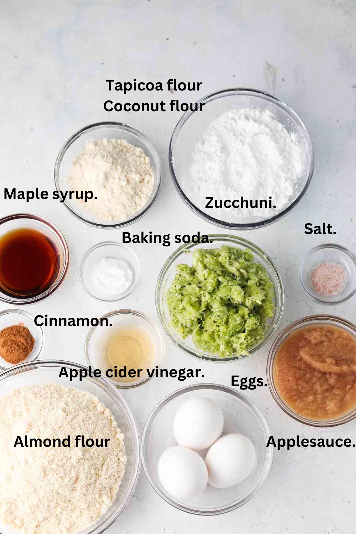 Homemade zucchini bread ingredients laid out on the counter in glass bowls.