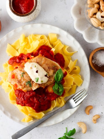 Paleo Chicken Parmesan on a white plate with basil