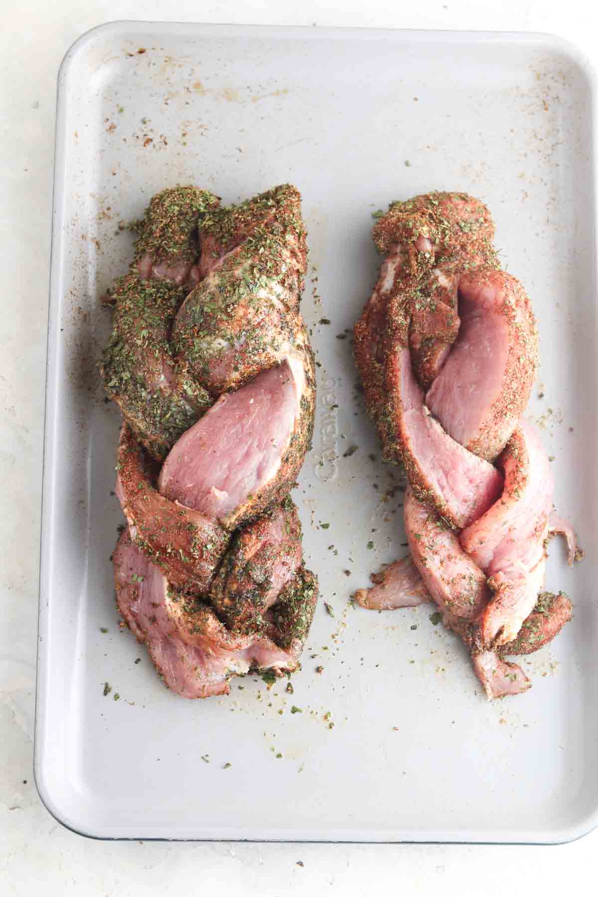 Braided pork tenderloin on a sheet pan.