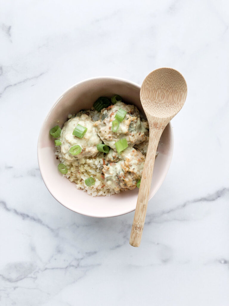 chicken meatballs with coconut curry in a light bowl on a white marble background