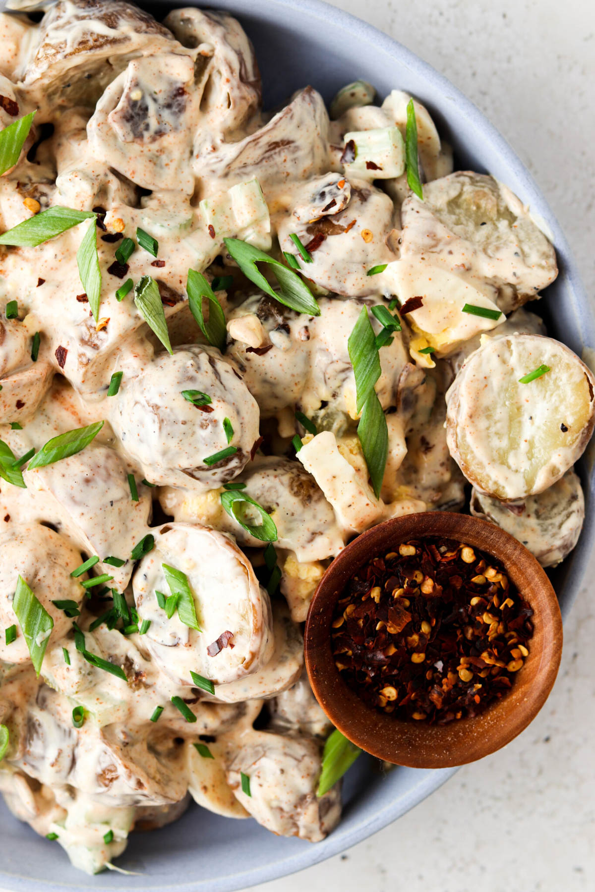 Paleo potato salad on a plate with green onion on top.