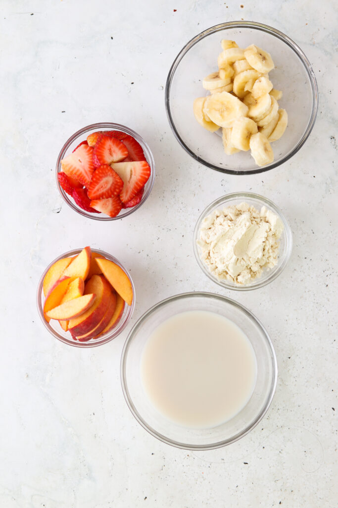 strawberry  peach smoothie ingredients laid out in a bowl