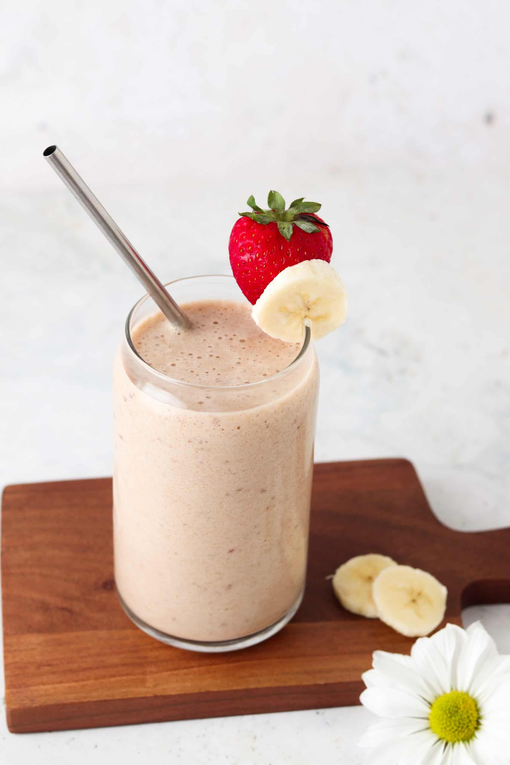 Strawberry peach smoothie in a glass with a strawberry on top.