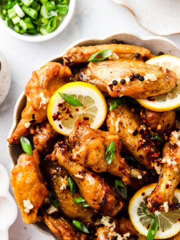 honey lemon chicken wings in a bowl with green onions