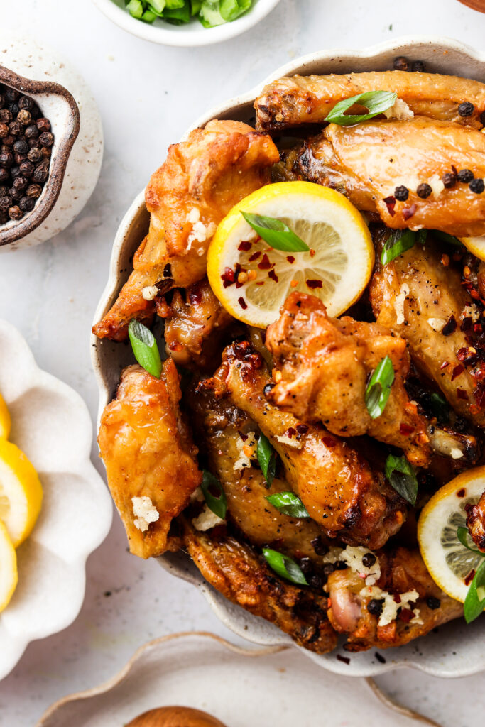 honey lemon chicken wings in a bowl with green onions