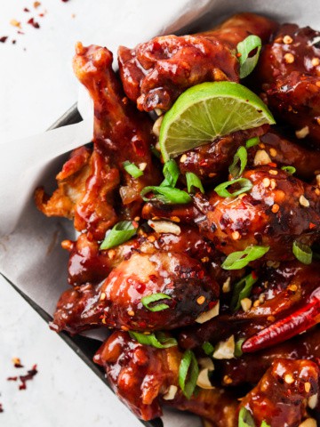 peanut butter and jelly chicken wings on a plate with limes