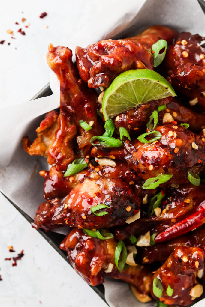 peanut butter and jelly chicken wings on a plate with limes