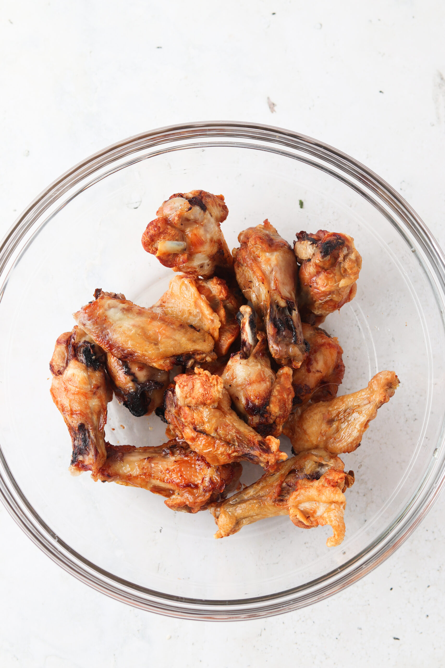 Air fried chicken wings in a glass mixing bowl.