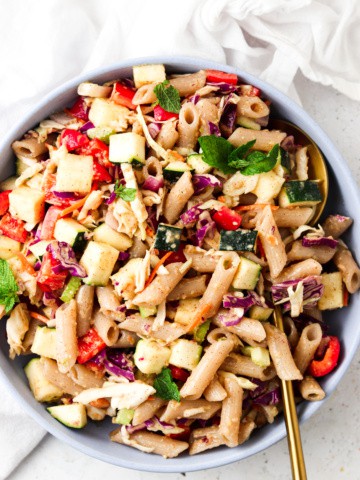 thai pasta salad in a blue bowl with a gold spoon