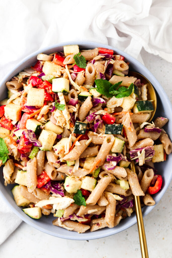 thai pasta salad in a blue bowl with a gold spoon