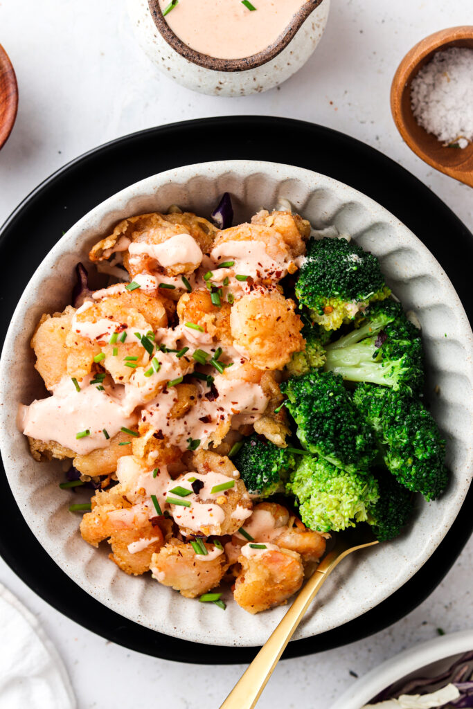 paleo bang bang shrimp with dairy free bang bang sauce in a bowl with broccoli