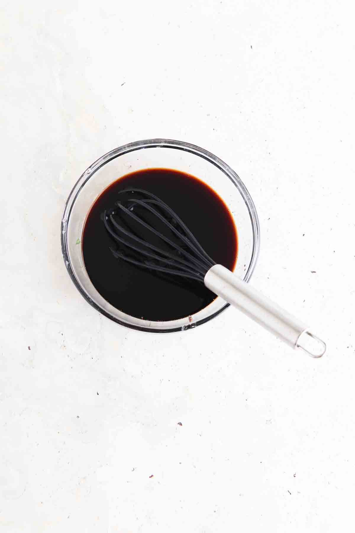 Balsamic maple glaze in a container with a whisk.