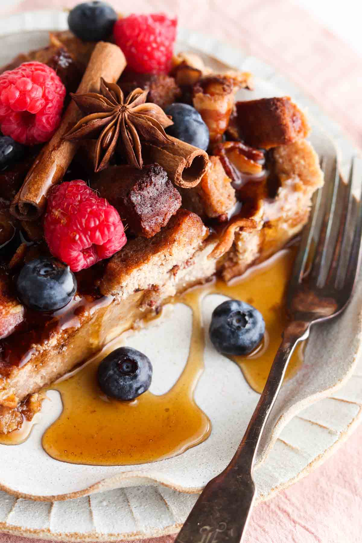 Slice of french toast on a plate with a pink napkin under it and fresh berries on top.