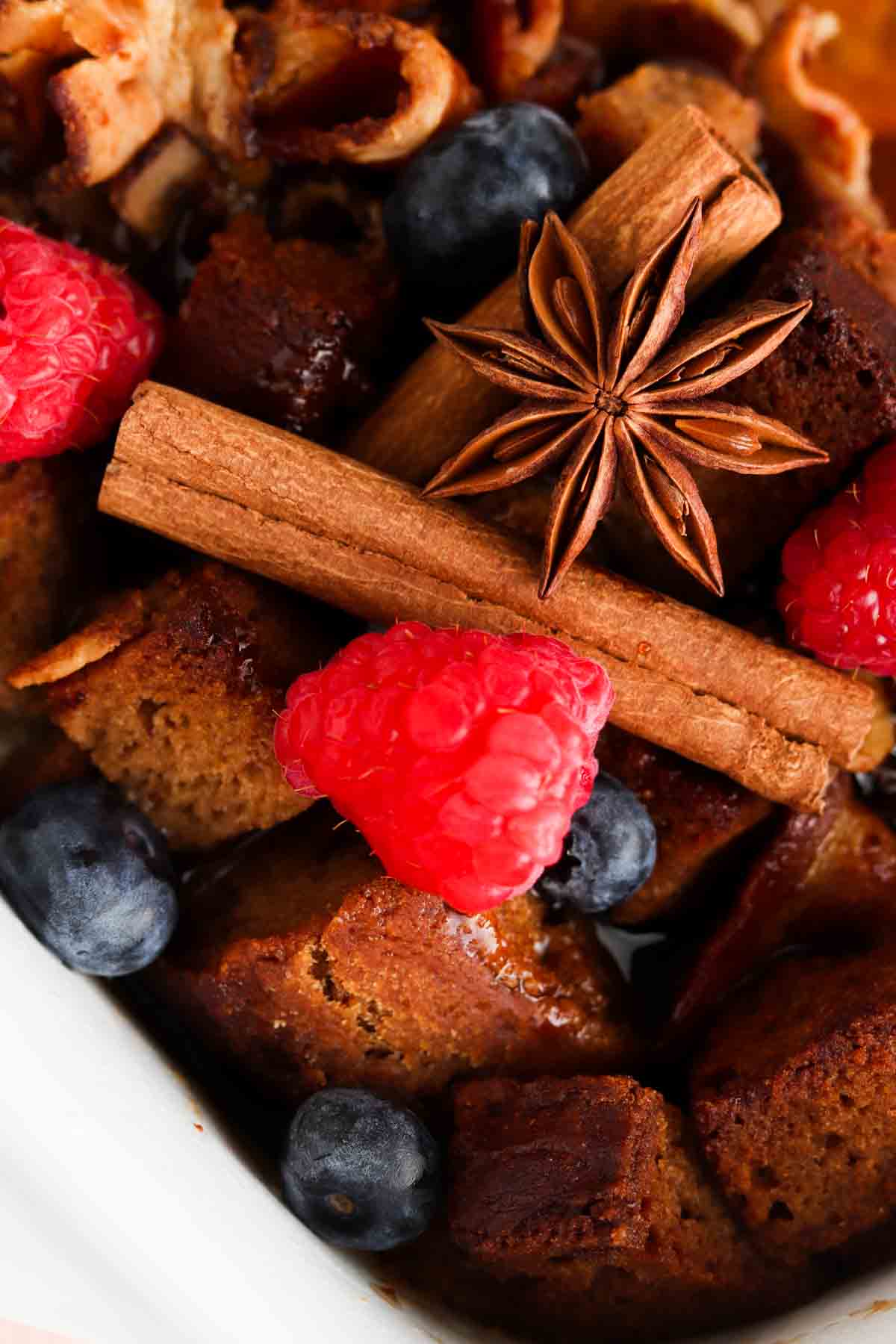 Close up photo of french toast casserole in a white pan with fresh berries on top.