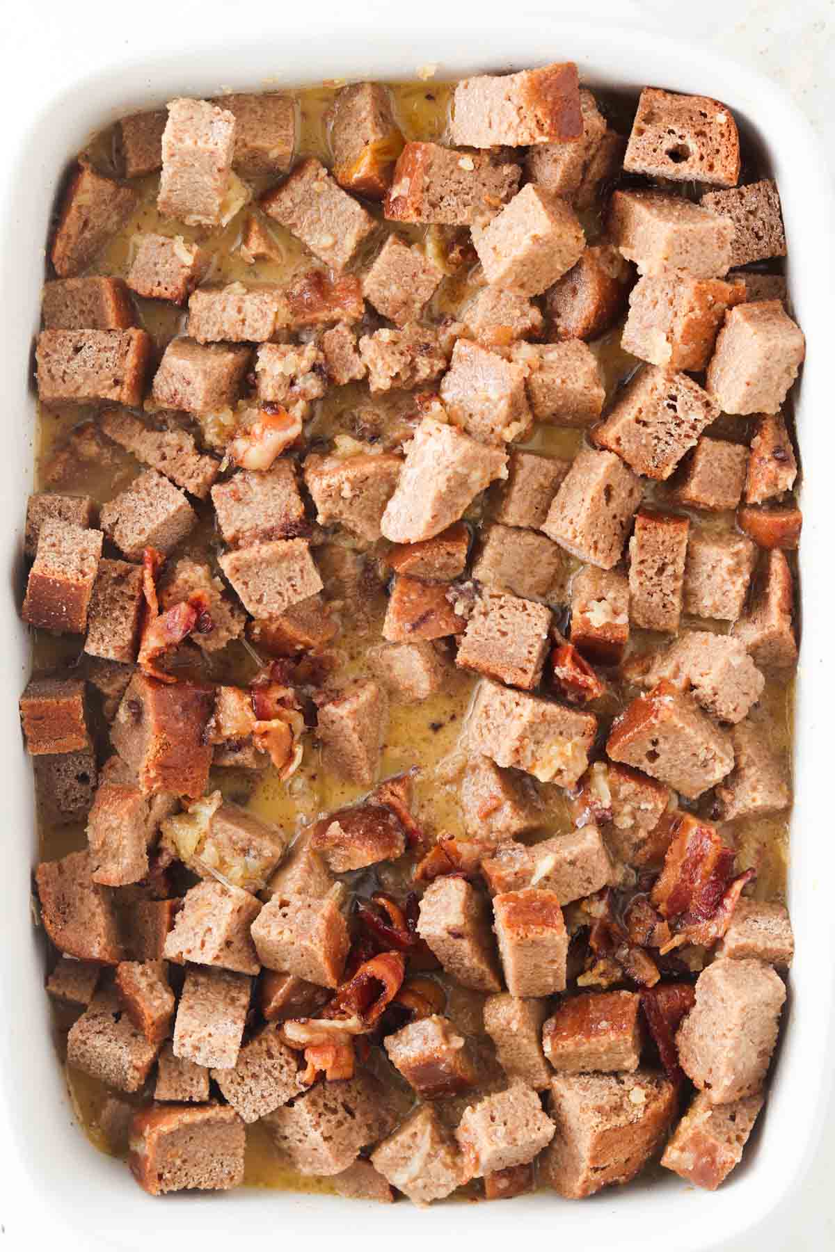 Cubed bread in a pan with french toast custard drizzled on top.