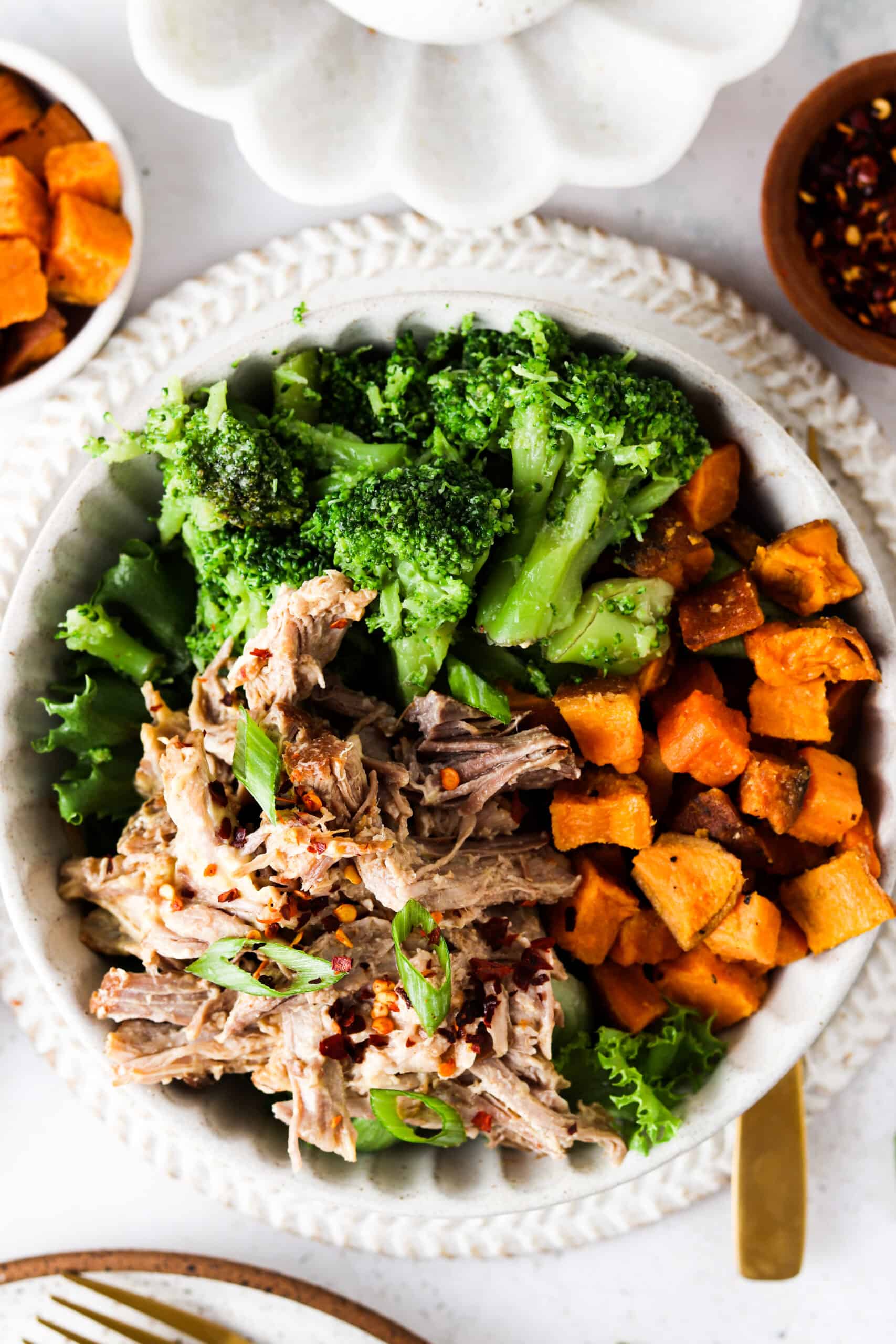 Pork butt in a bowl with sweet potatoes and broccoli.