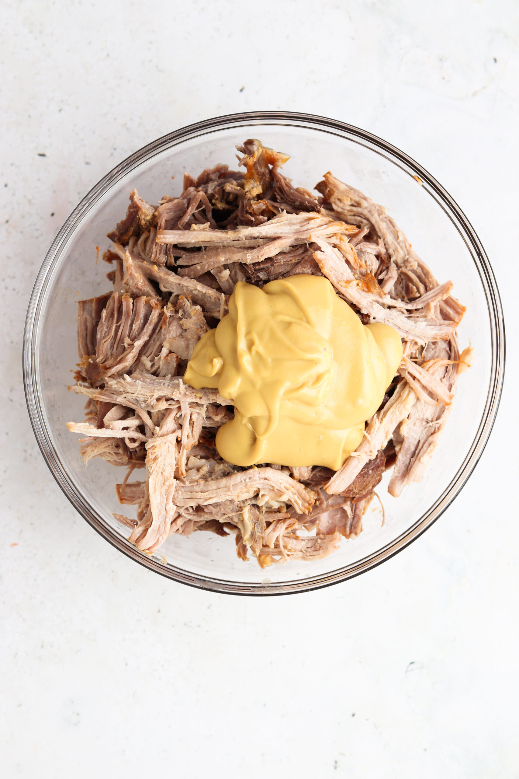 Pork butt with honey mustard on top in a glass bowl. 