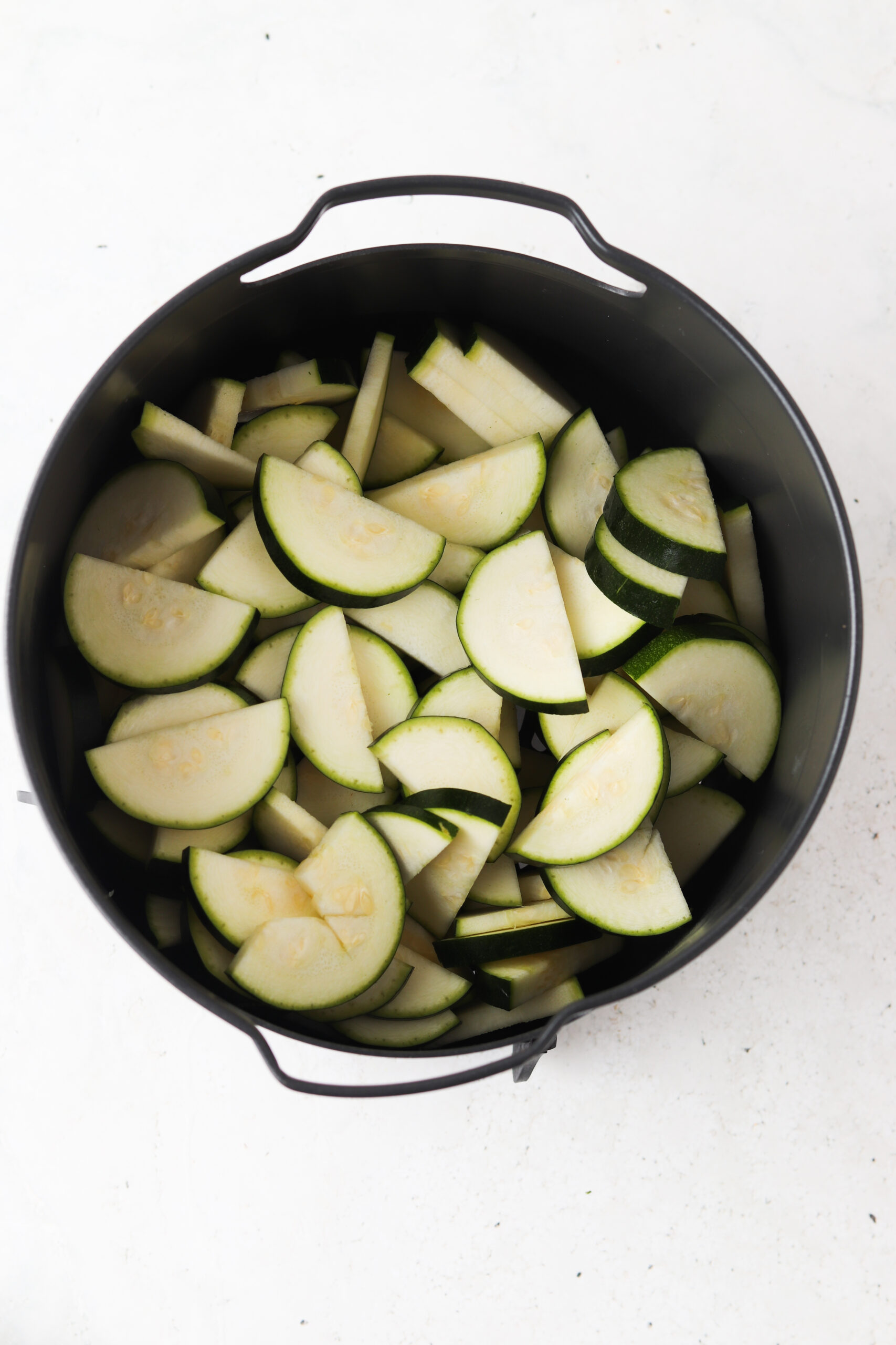 Zucchini sliced in half moons in the basket of an instant pot. 