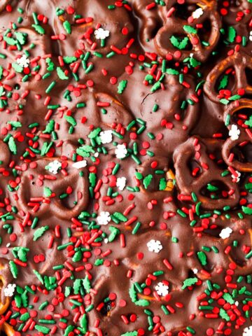 Chocolate covered pretzels on a sheet pan with sprinkles on top.