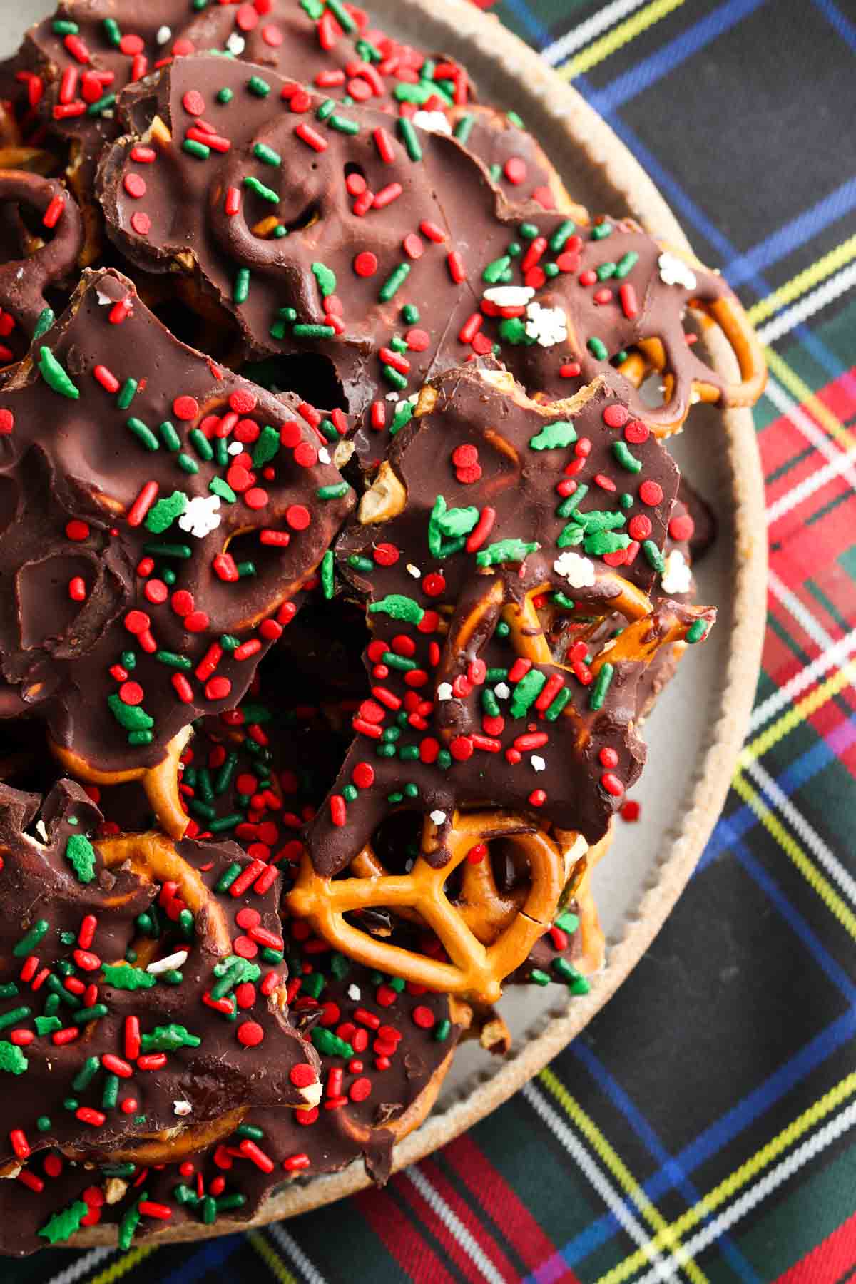 Chocolate covered pretzels on a plate with sprinkles on top.