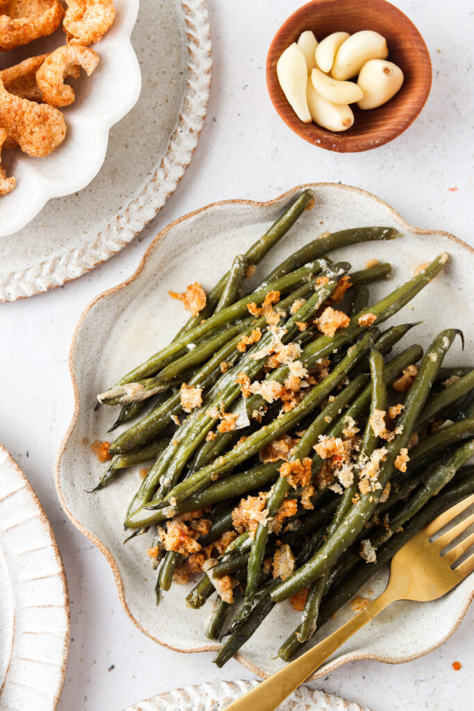 Beautiful green bean casserole on a plate with pork rinds on top.