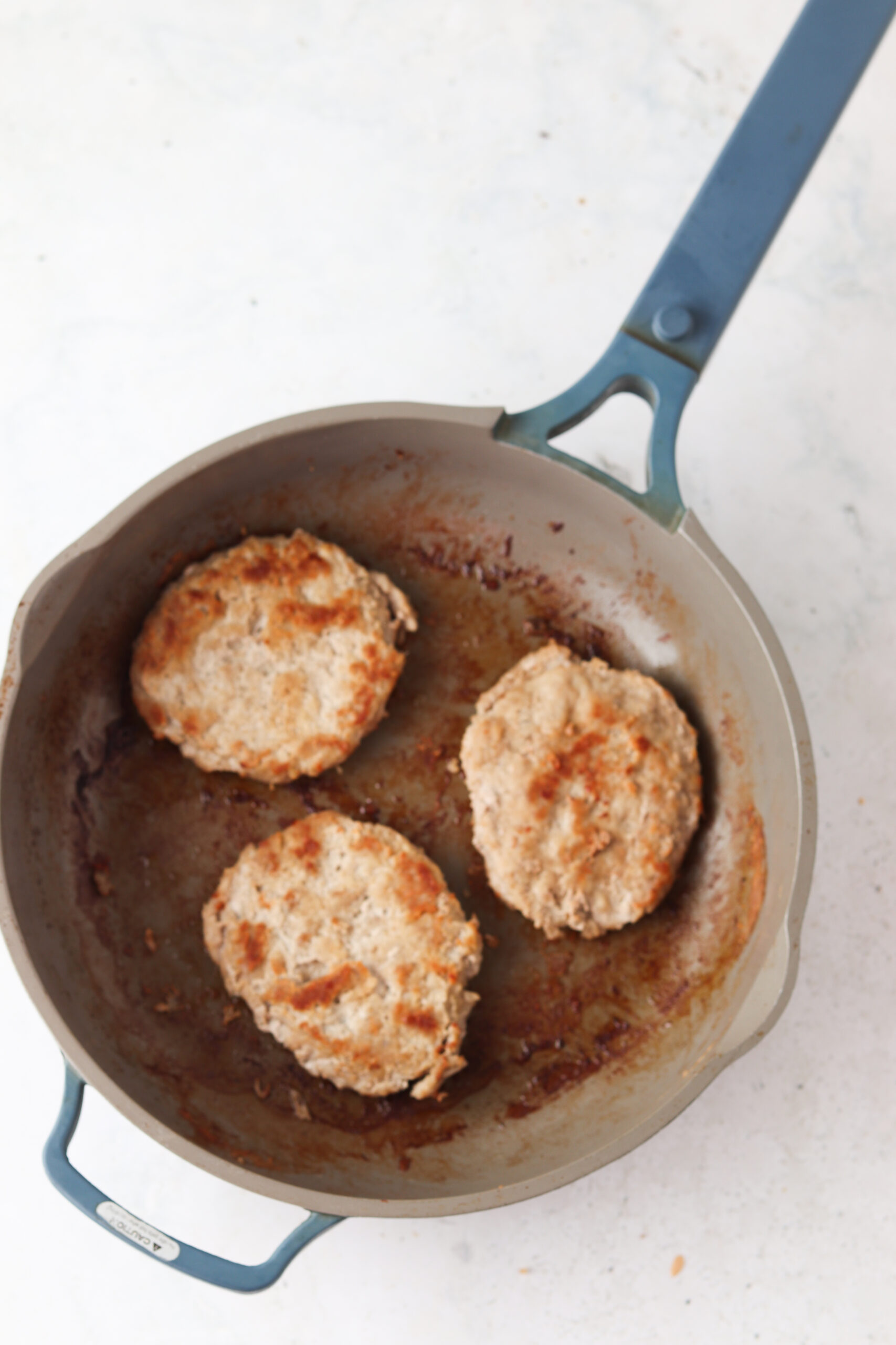 Cooked frozen burger patties in a skillet.