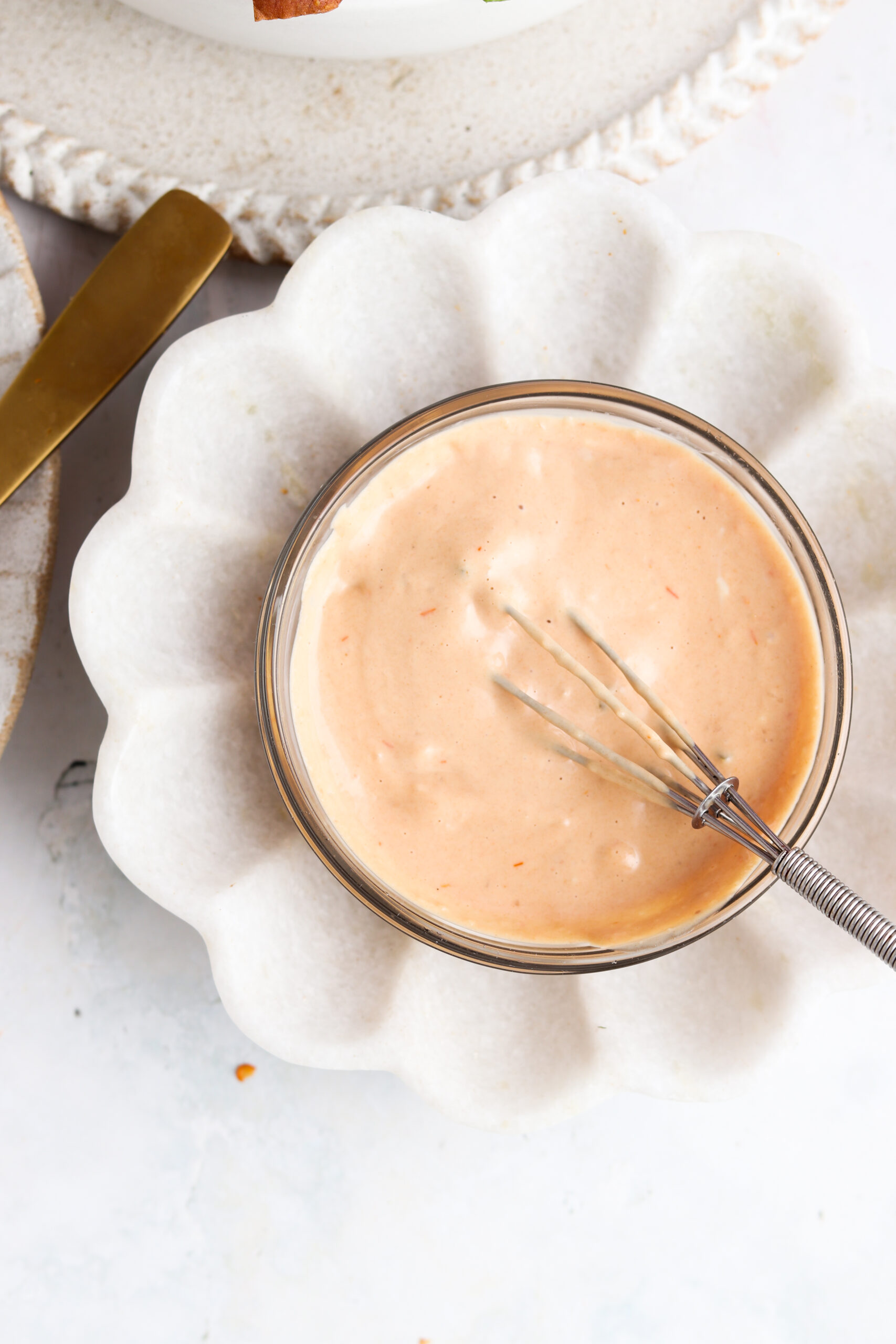 Homemade special sauce in a small glass bowl with a small whisk.