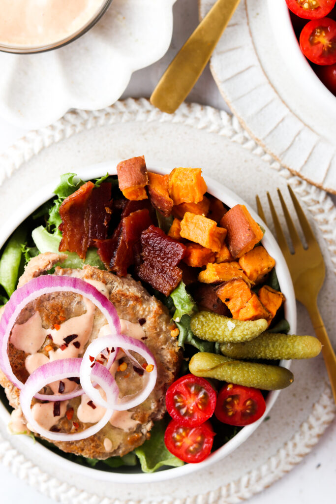 deconstructed burger bowls with sweet potatoes, pickles, tomatoes, and bacon