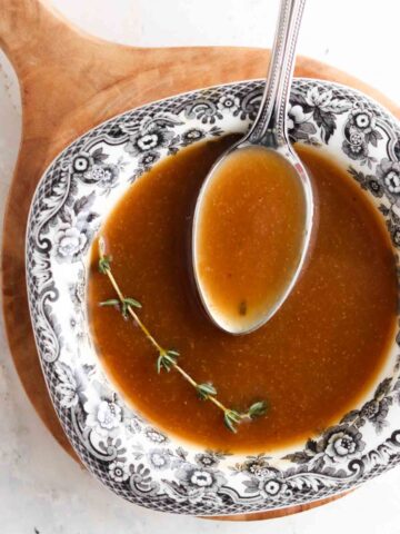 Dairy free gravy in a bowl with a piece of fresh thyme on top.