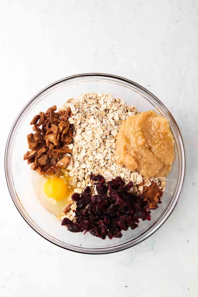 oats, eggs, cranberries, apples, almond milk, and cinnamon in a bowl