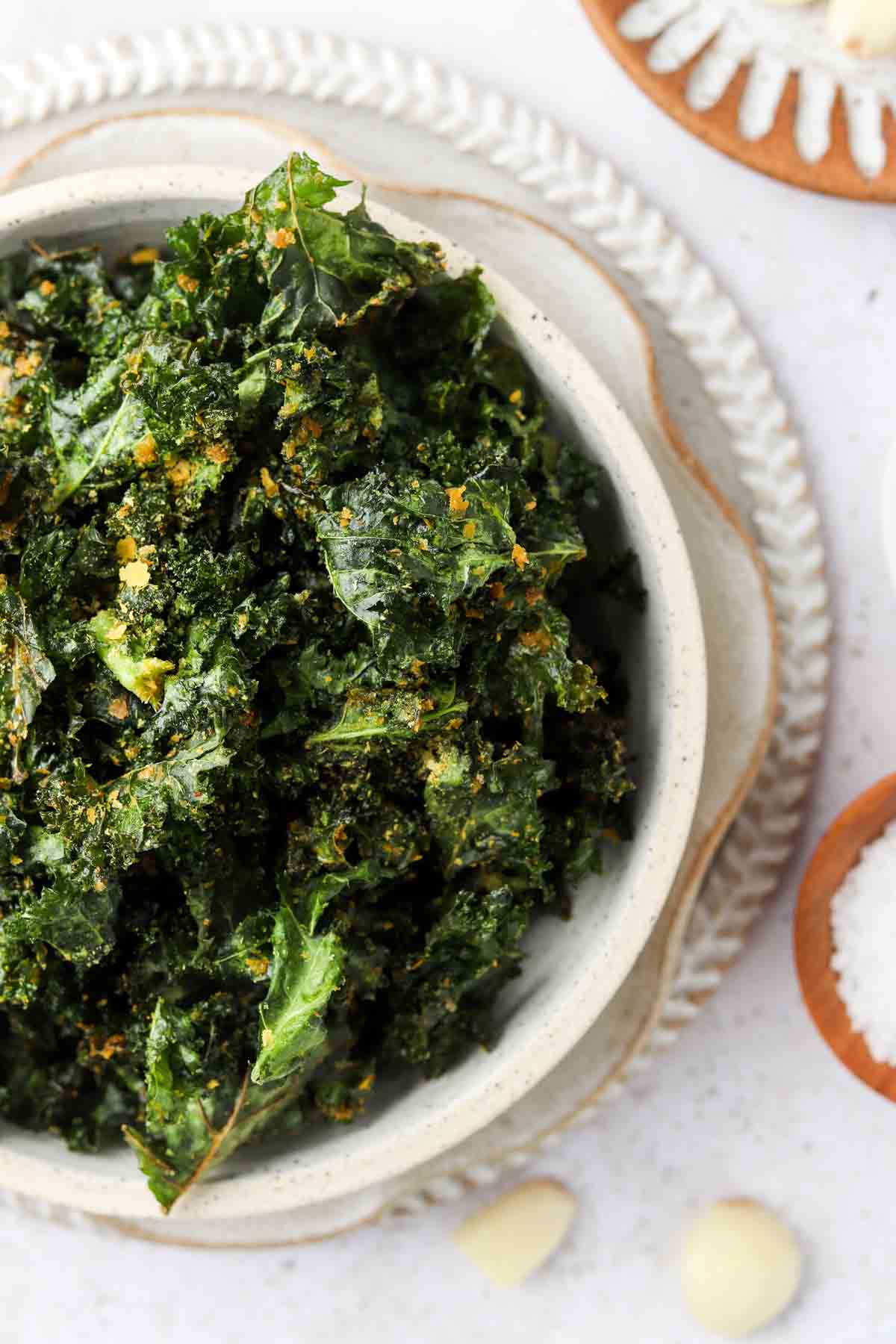 Kale chips in a bowl with nutritional yeast garnish. 