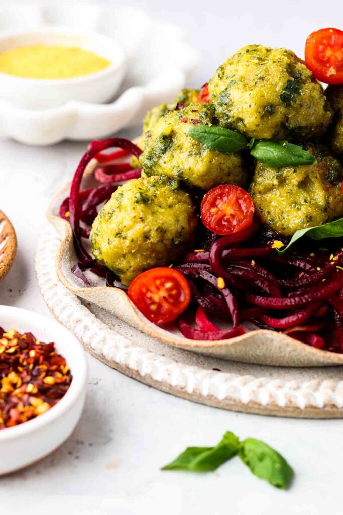 side shot of gluten free pesto meatballs on beet noodles