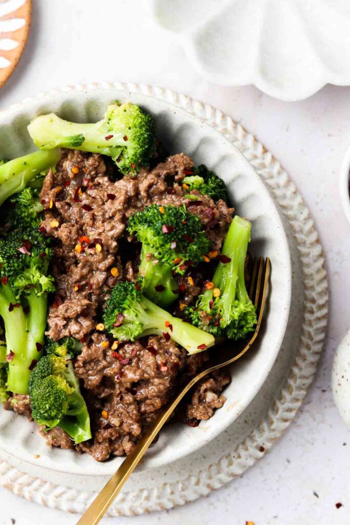 keto beef and broccoli in a bowl with a bowl with red pepper flakes