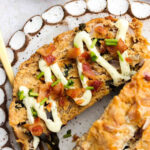 Slice of keto meatloaf on a plate with dairy free ranch and bacon.
