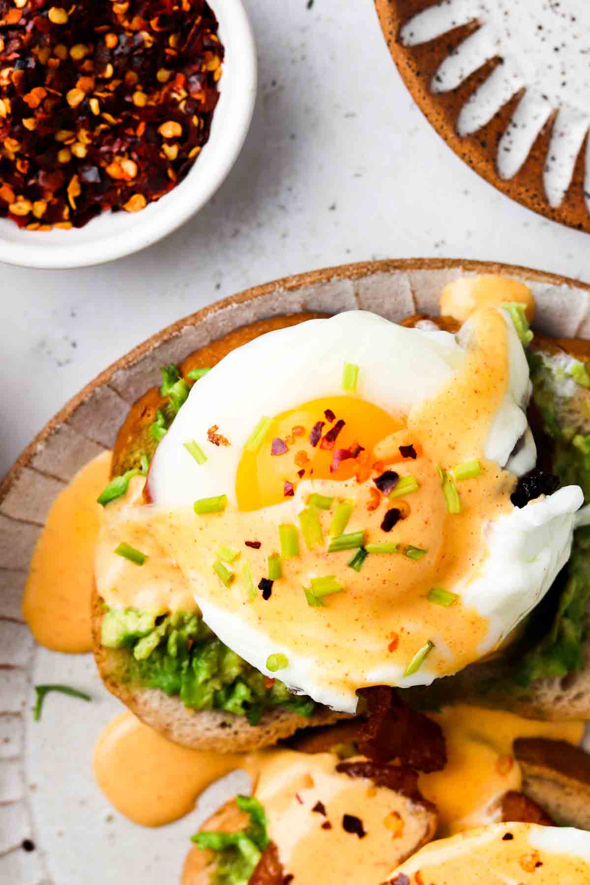 Dairy Free Hollandaise Sauce over toast and eggs and garnished with fresh green herbs.