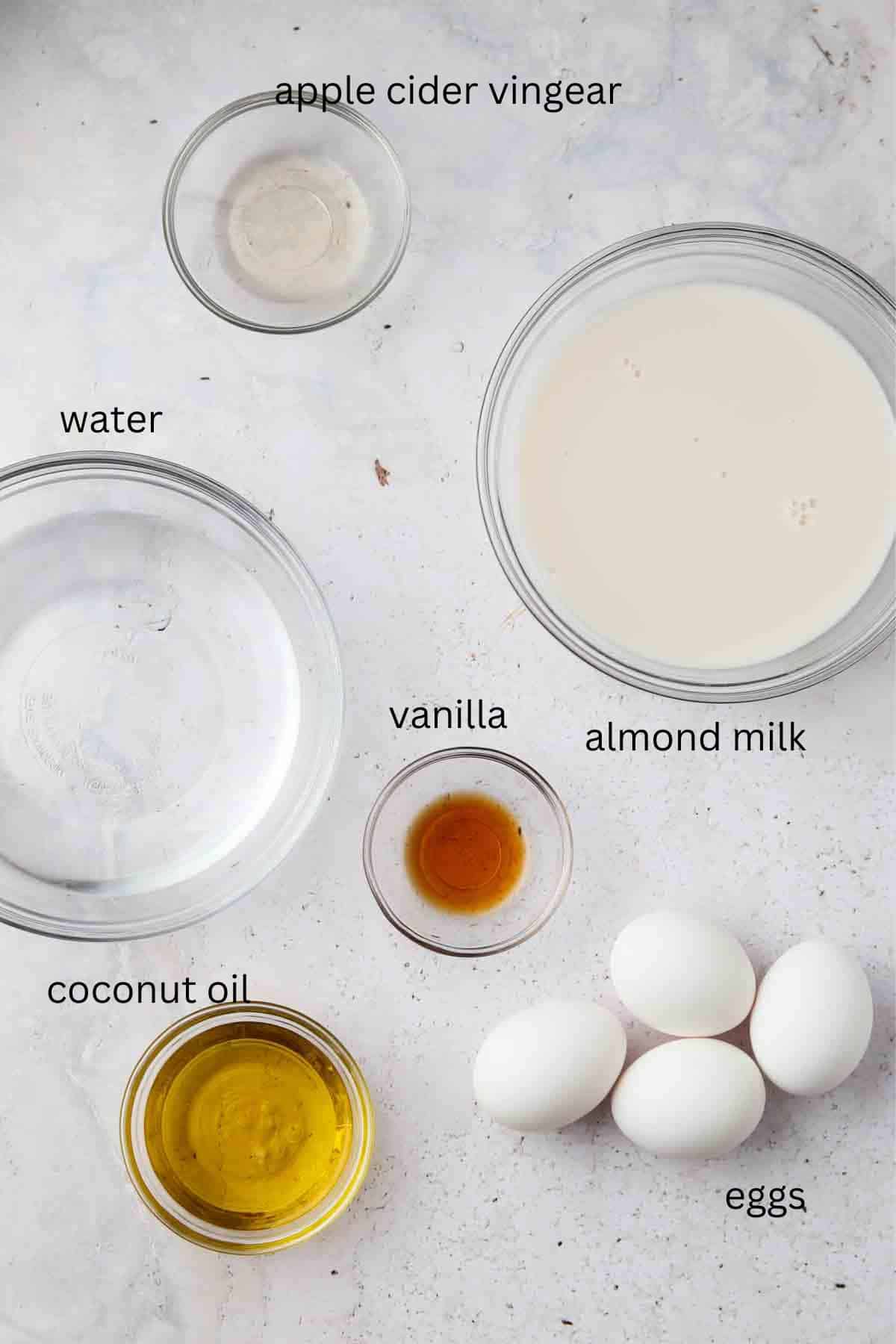 Wet ingredients for chocolate cake in small glass bowls on a counter.  