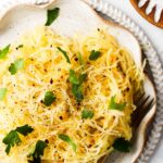 Easy air fryer spaghetti squash on a plate with fresh green herbs.