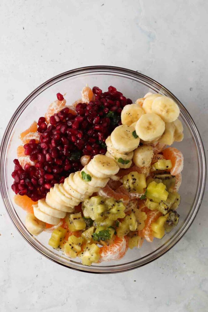 pomegranate, mint, bananas, and kiwi in a bowl