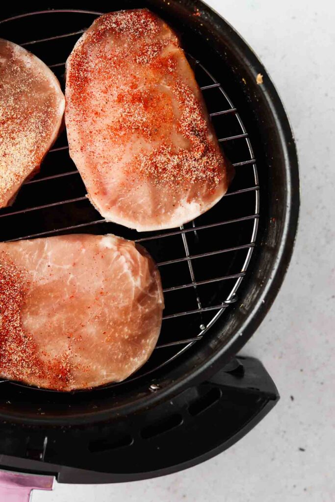 raw pork chops on a rack in the air fryer
