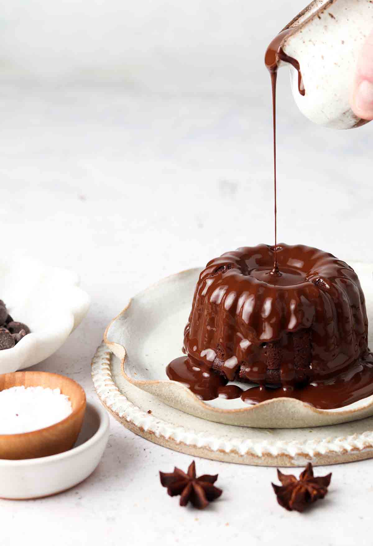 Mini chocolate cakes with dairy free chocolate ganache being drizzled on top.