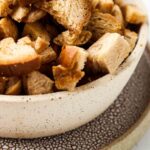 gluten free croutons in a bowl with a plate under it