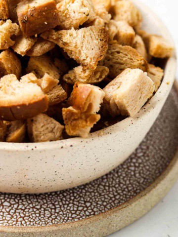 gluten free croutons in a bowl with a plate under it