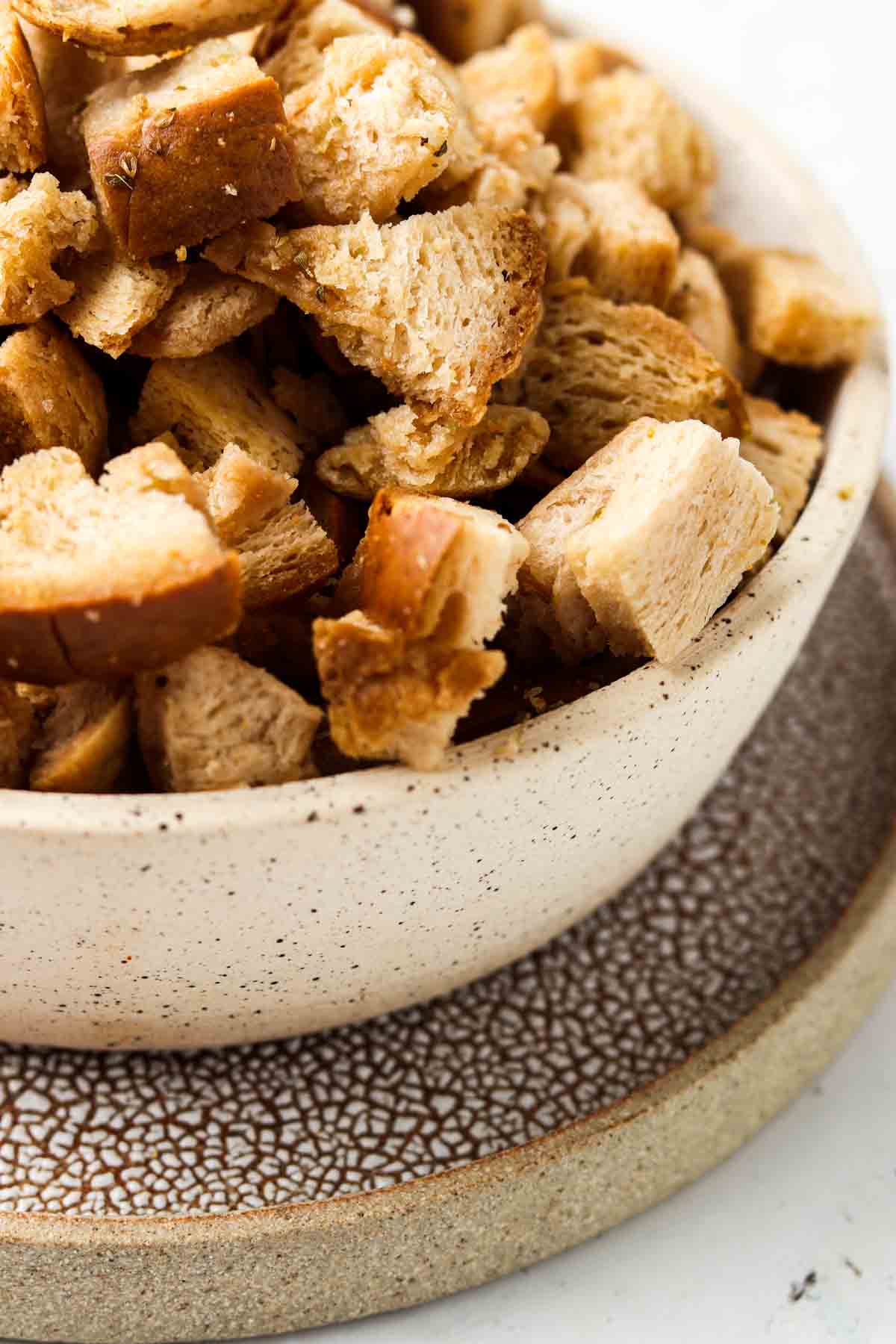 Gluten free croutons in a bowl with a plate under it.